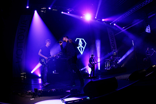 Andreas Bourani and his band performing on stage under purple lights