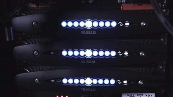 Three Powersoft X8 amplifiers in a rack with front LEDs lit and IP address labels
