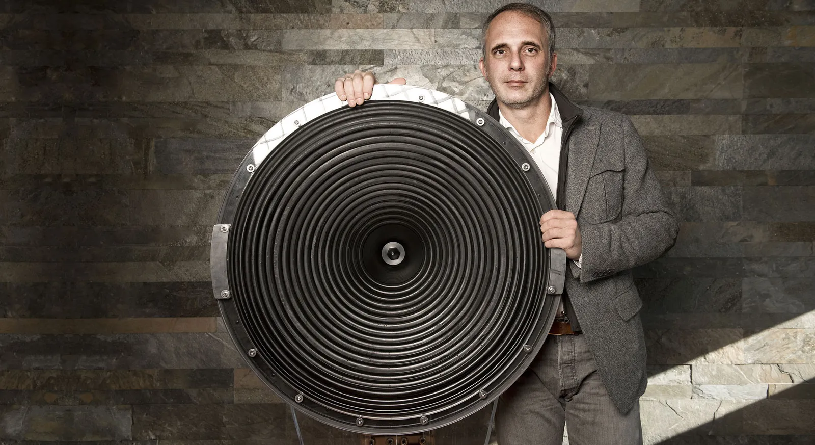 Claudio Lastrucci next to a large ribbed loudspeaker diaphragm