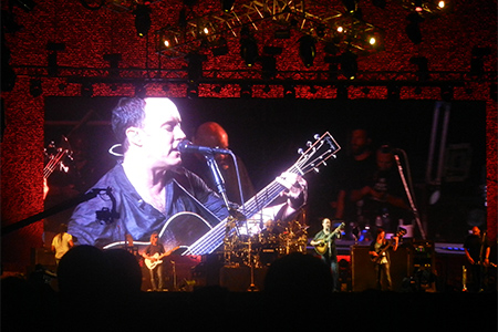 Video screen showing Dave Matthews singing and playing guitar, above the band on stage