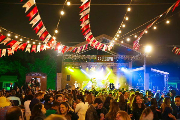 Crowd in front of the Fervo stage under string lights and bunting at Arraial do Fervo, São Paulo
