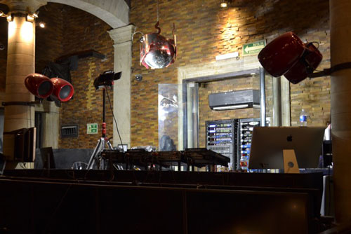 Grill nightclub DJ booth with red suspended loudspeakers, a mirror ball and equipment racks