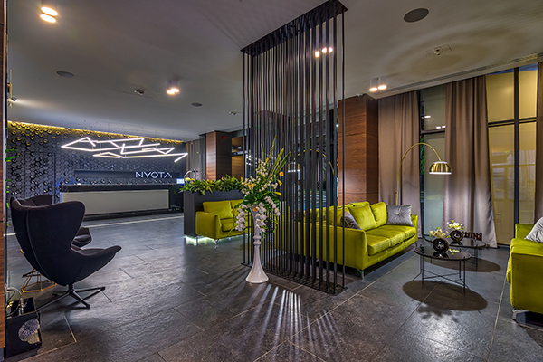 Hotel Nyota lobby with reception desk, green sofas and ceiling loudspeakers