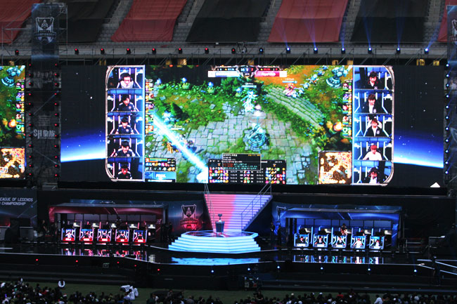 League of Legends World Finals stage in Seoul's Sangam Stadium, with a giant screen and two team booths