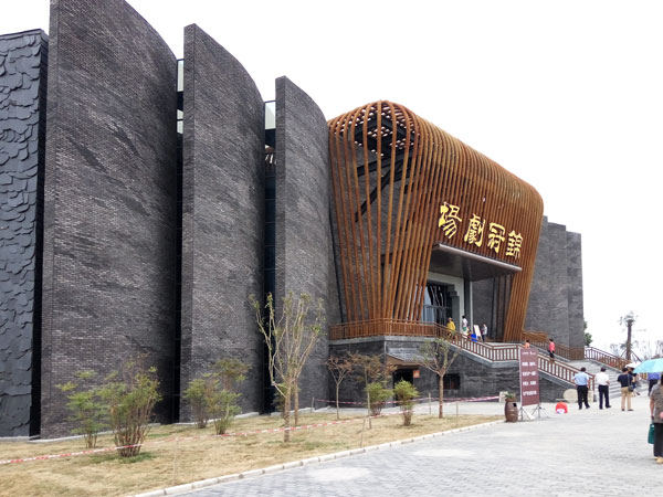 Jinguan Theatre exterior with dark brick walls and a curved wooden-slat entrance