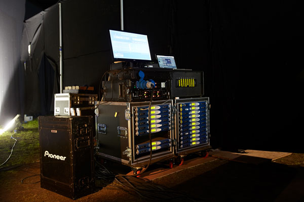Backstage amplifier racks with blue Powersoft K Series amplifiers and a control laptop at Lovebox