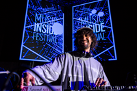 DJ at the decks in front of Music Inside Festival screens