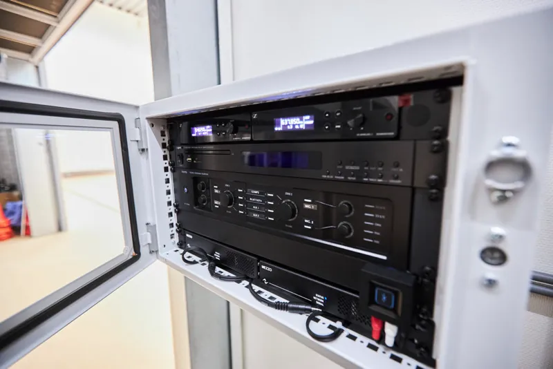 Open wall cabinet with Sennheiser wireless receivers, a media player, a mixer amplifier and a Mezzo amplifier