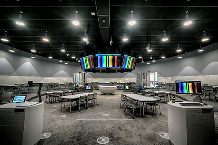 Monash University round teaching space: ring of screens hanging at the centre, group tables and lecterns