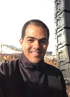 Smiling man in front of a flown line array at an outdoor event