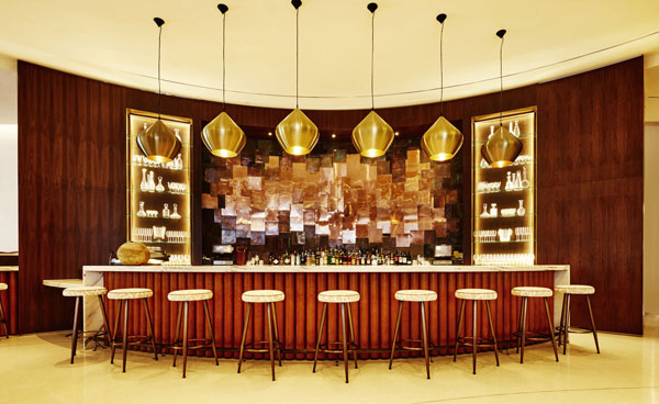 Nautilus Hotel South Beach bar with a curved counter, gold pendant lamps and stools