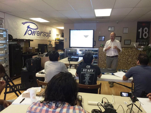 Trainer speaking to participants under a Powersoft banner during the technical training in Miami