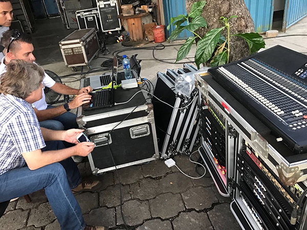 Technicians at a laptop beside a mixing console and amplifier racks during the training in Managua