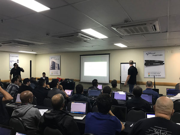 Instructor at a flip chart and attendees with laptops at the Armonía seminar in São Paulo