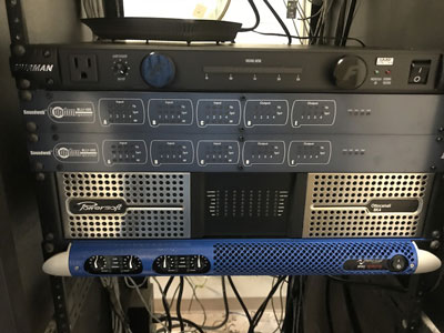Installed rack with Powersoft Ottocanali and blue Powersoft amplifiers below two Soundweb processors