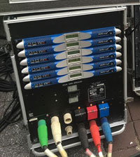 Rack case with six blue Powersoft K Series amplifiers above color-coded power connectors