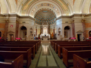 Basilica of Regina Pacis interior: nave with wooden pews, altar and painted apse dome