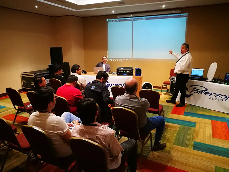 Powersoft demo room: a presenter points at a projected screen, attendees seated