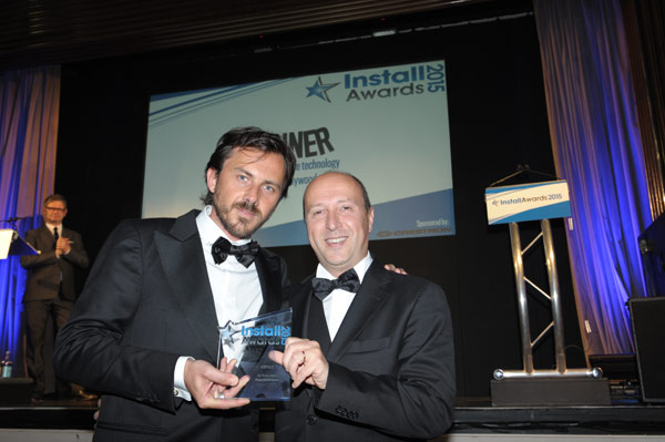 Two men in dinner jackets holding the InstallAwards 2015 trophy on stage