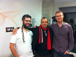 Three men posing in front of the DN'A Systems logo