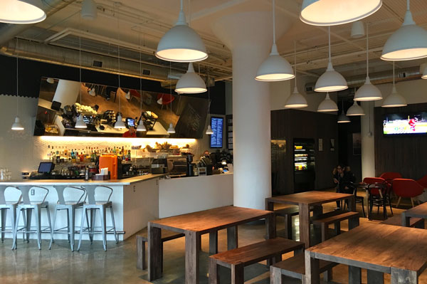 Restaurant area with a bar counter, pendant lamps and wooden tables