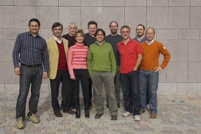 Group of people in casual clothes posing outdoors in front of a stone-clad wall