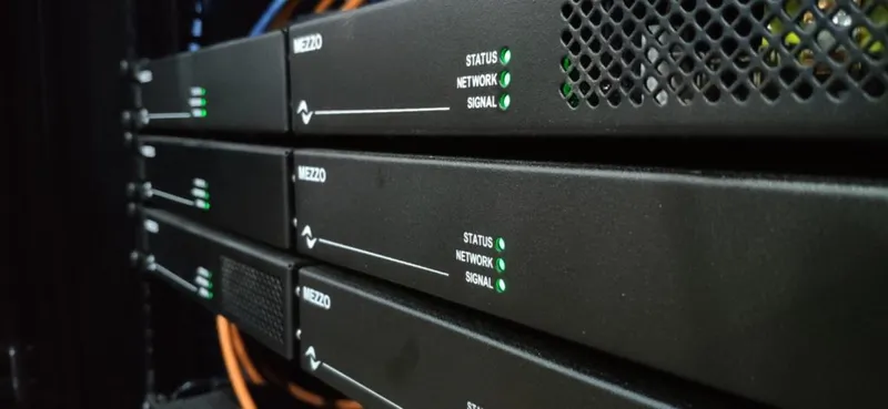 Mezzo amplifiers mounted in pairs in a rack, close-up of front panels with green status LEDs