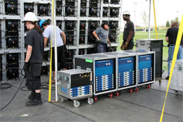 Crew members beside wheeled amplifier racks at the Mile High Music Festival, with stacked equipment cases behind