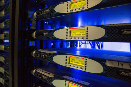 Close-up of Powersoft K Series amplifiers in a rack under blue light