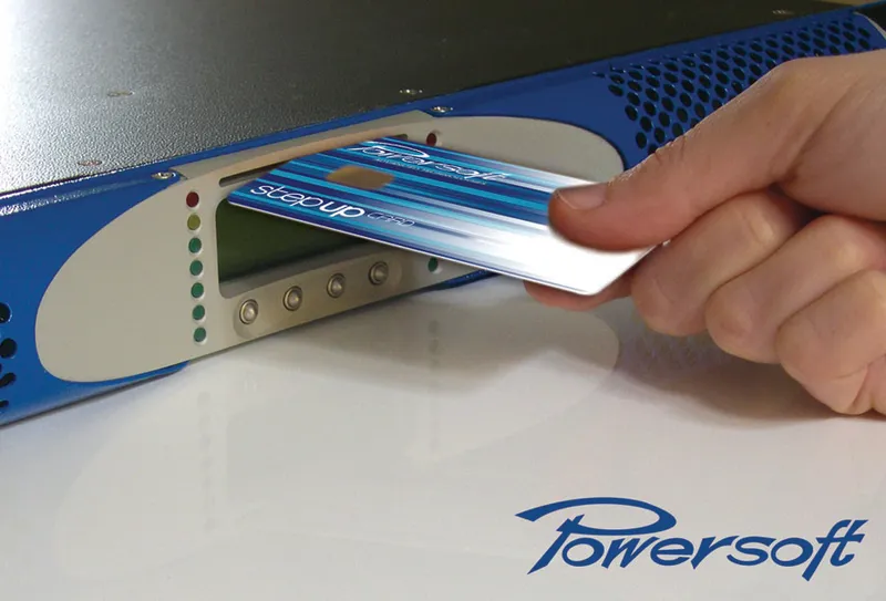 Hand inserting a Powersoft Step-Up card into the front-panel slot of an amplifier