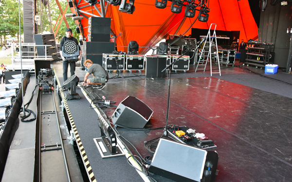 Crew setting up the Red Hot Chili Peppers stage, with floor wedges and a guitar pedalboard