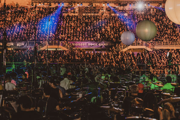 Hundreds of drummers on the stadium pitch, with packed stands and a Biggest Rock Band banner behind