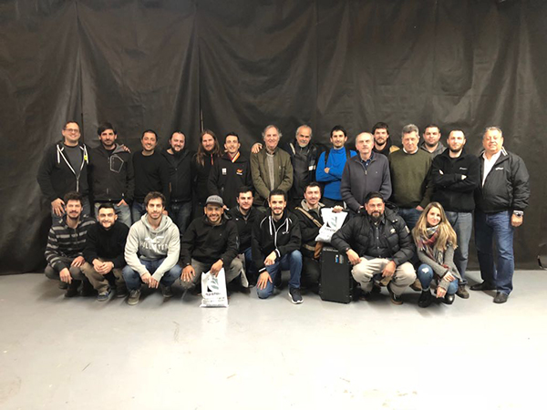About 25 seminar participants posing in two rows in front of a black curtain