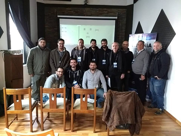 Twelve seminar participants posing in a room with a projector screen and an Armonía banner